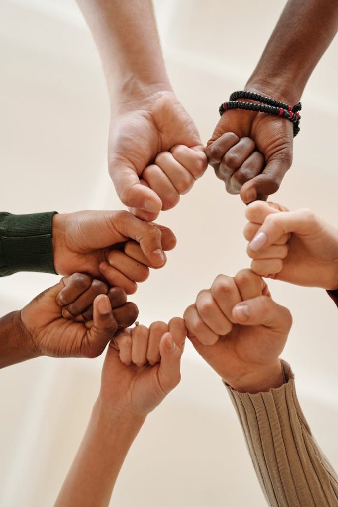close-up-of-people-bumping-fists-6146704 Hands of diverse people fist bumping, symbolizing unity and teamwork.